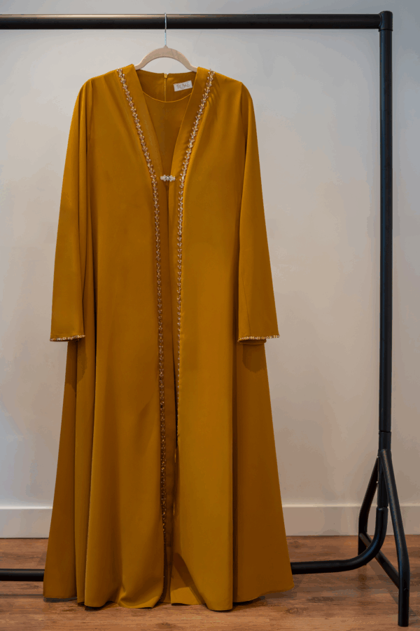 Front view of the Mustard Adoria Abaya on hanger – hand-embellished design