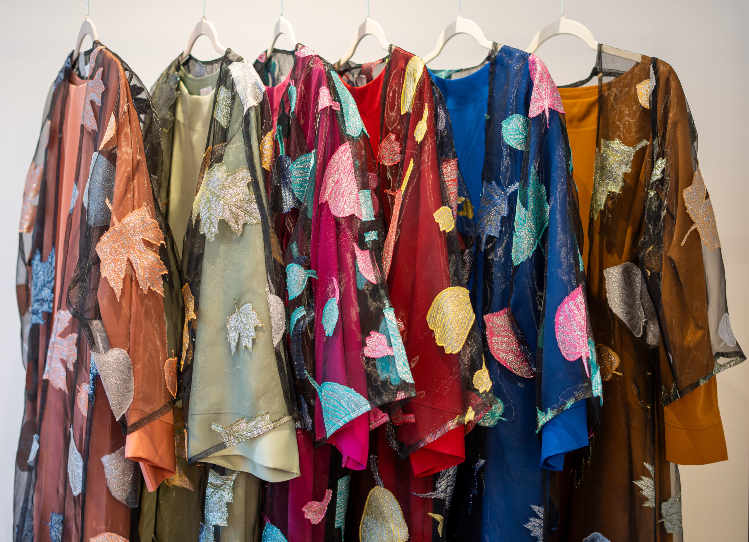 Autumn Bloom embroidered abaya — full front view showing all colourways (Red, Fuchsia, Royal Blue, Mustard, Cream Peach, Pistachio Green).