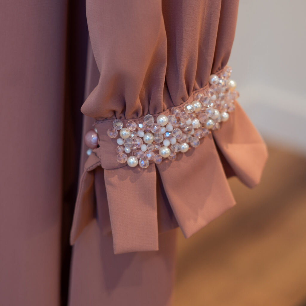 Nova kimono-style long dress — close-up of hand-beaded sleeve cuff with pearls and crystals in nude