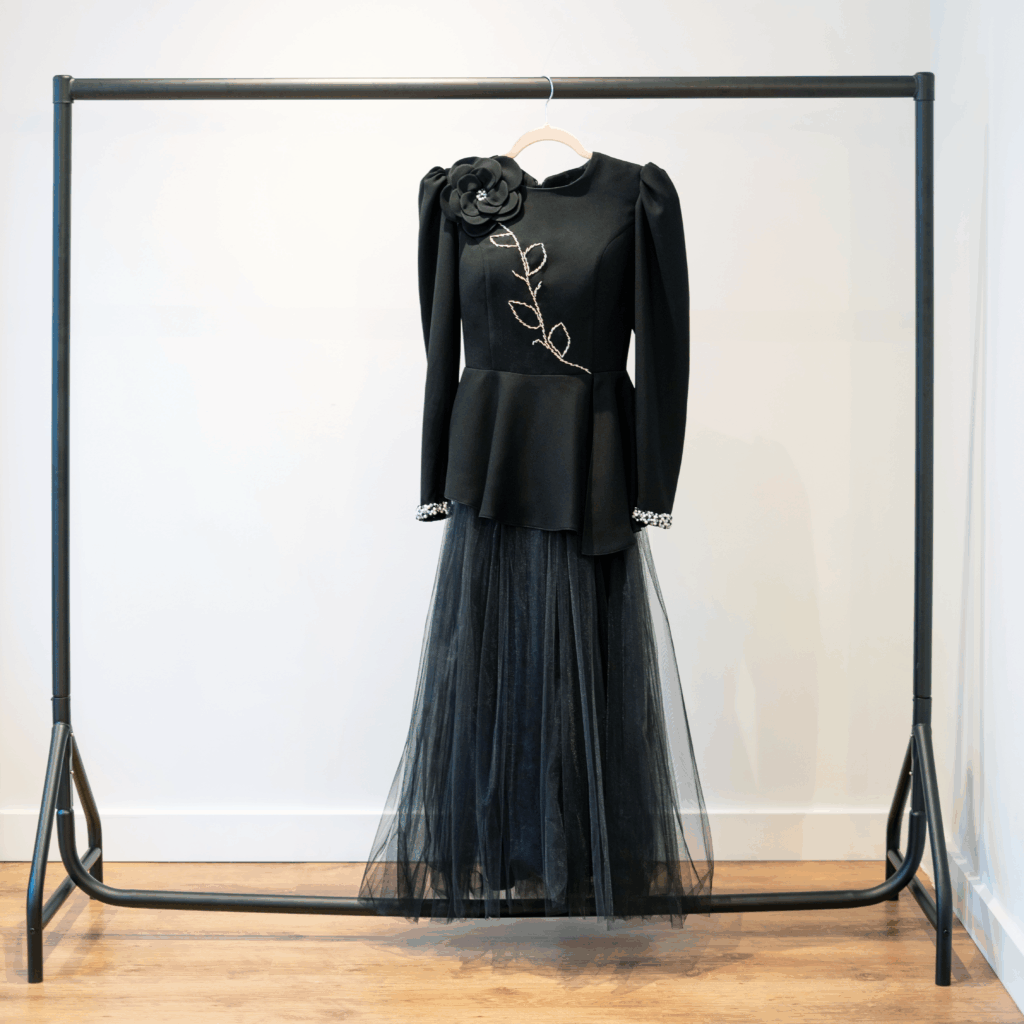 Black peplum couture jacket with hand-beaded floral design and matching black tulle skirt on hanger.