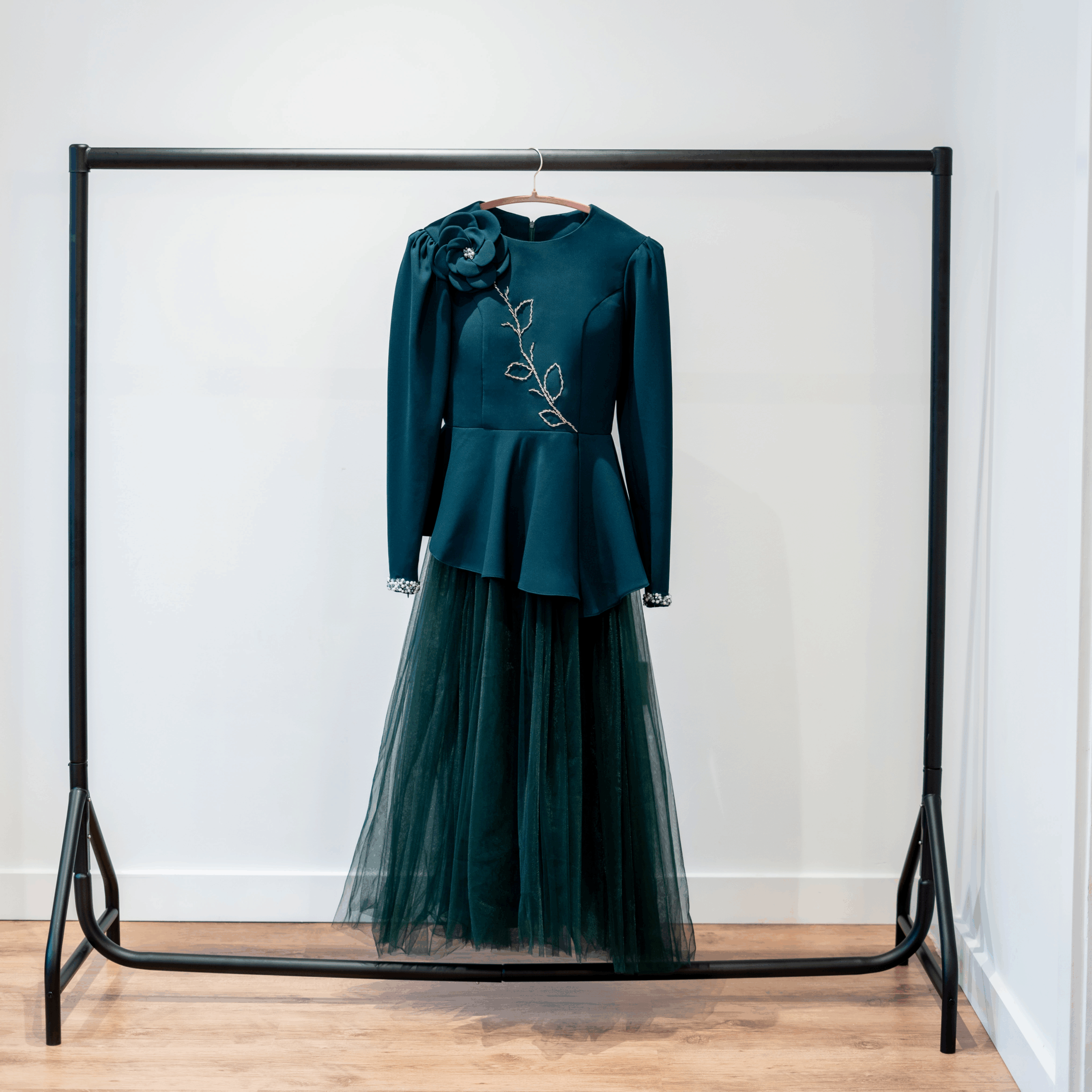 Close-up view of dark green couture jacket featuring floral hand-beading and shoulder flower appliqué.