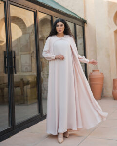 Handmade cream waterfall dress with flowing silhouette, long sleeves, and hand-embroidered stone and bead detailing.