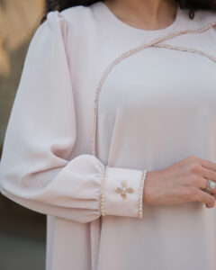 Close-up of handmade cream waterfall dress sleeve with hand-embroidered stone and bead embellishments.
