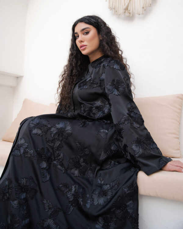 Black abaya with floral textured fabric, flowing silhouette and hidden front buttons
