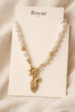 Royaé gold pendant pearl necklace on beige jewelry card with soft neutral background