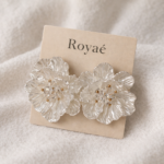 Royaé transparent floral statement earrings with gold center on beige jewelry card