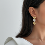 Royaé gold and pearl heart drop earrings worn by model